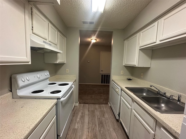 kitchen with a sink, white appliances, a textured ceiling, wood finished floors, and under cabinet range hood