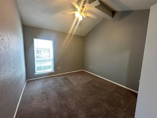 spare room with ceiling fan, lofted ceiling with beams, dark colored carpet, and a textured ceiling