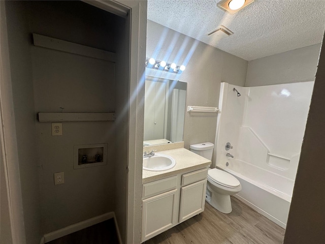 bathroom with vanity, wood finished floors, toilet, shower / tub combination, and a textured ceiling