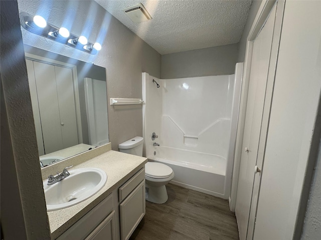 full bathroom featuring visible vents, vanity, a textured wall, wood finished floors, and a textured ceiling