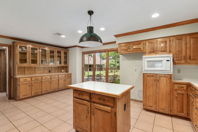 kitchen featuring light tile patterned flooring, light countertops, white microwave, ornamental molding, and glass insert cabinets