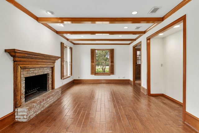 unfurnished living room with ornamental molding, a brick fireplace, wood finished floors, beam ceiling, and baseboards