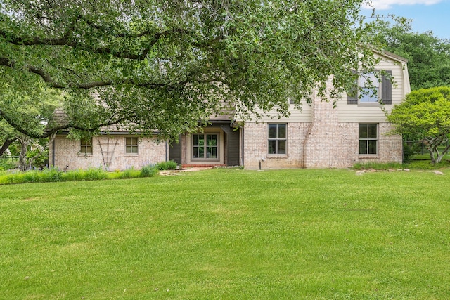 rear view of property with a yard and brick siding
