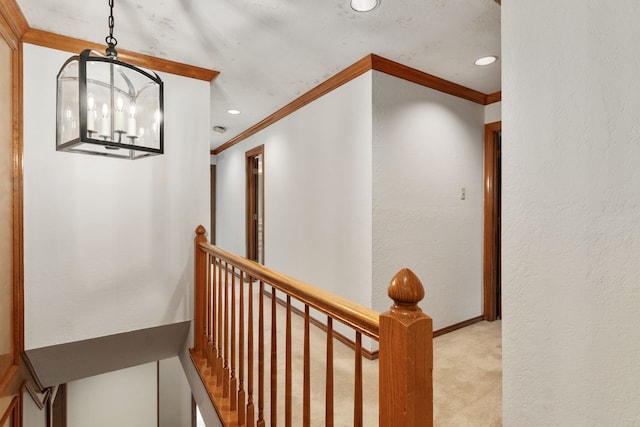corridor with an inviting chandelier, crown molding, recessed lighting, light colored carpet, and an upstairs landing