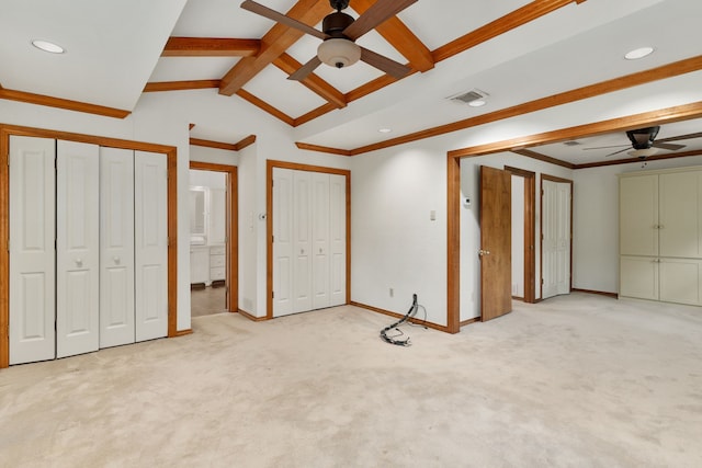 unfurnished bedroom featuring visible vents, lofted ceiling with beams, multiple closets, and light carpet