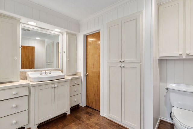 bathroom featuring toilet, ornamental molding, wood finished floors, and vanity