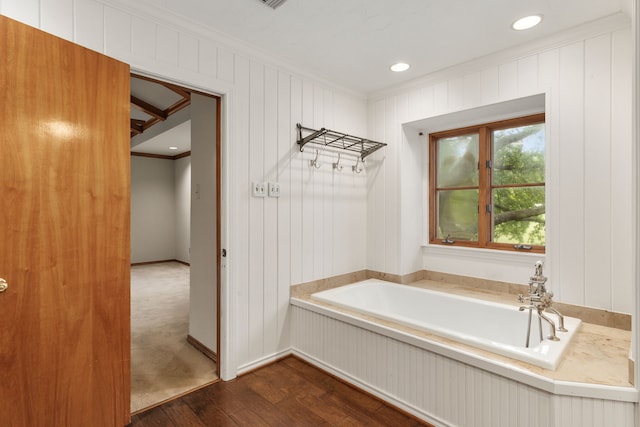 bathroom featuring a bath, ornamental molding, and hardwood / wood-style flooring