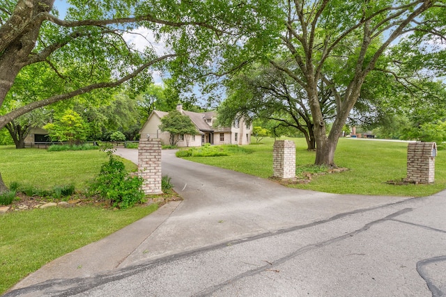 view of front of house featuring a chimney, a front yard, and aphalt driveway