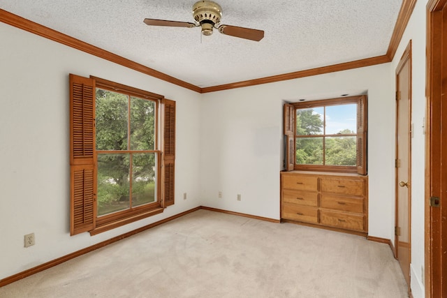 empty room featuring a ceiling fan, ornamental molding, a healthy amount of sunlight, and light carpet