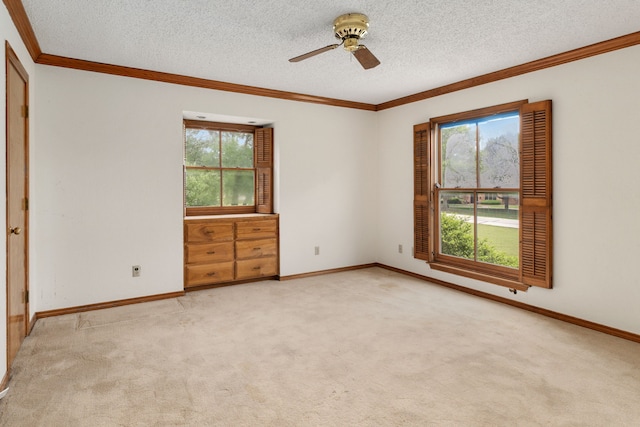 carpeted spare room with crown molding, a ceiling fan, a textured ceiling, and a wealth of natural light