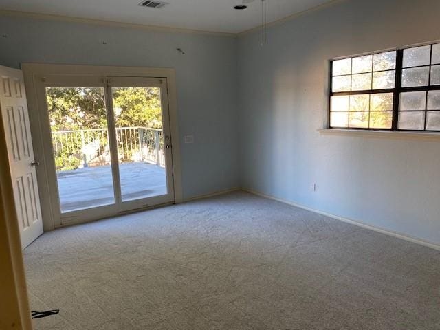 spare room featuring carpet flooring, baseboards, visible vents, and crown molding