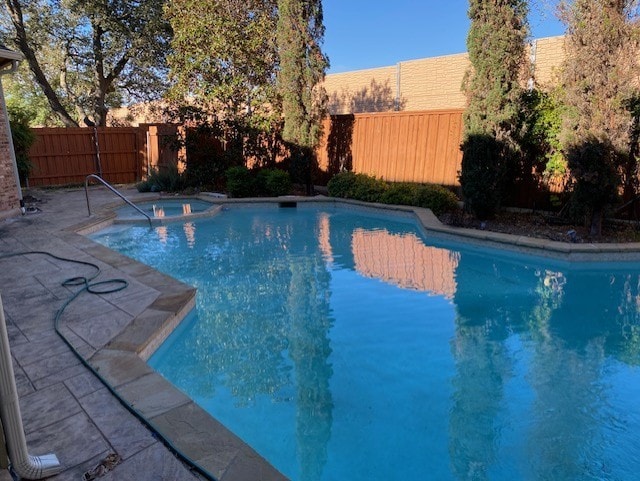 view of pool featuring a pool with connected hot tub, a fenced backyard, and a patio area