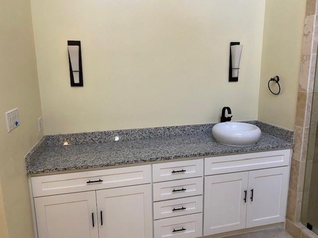 full bathroom with double vanity, a tile shower, and a sink