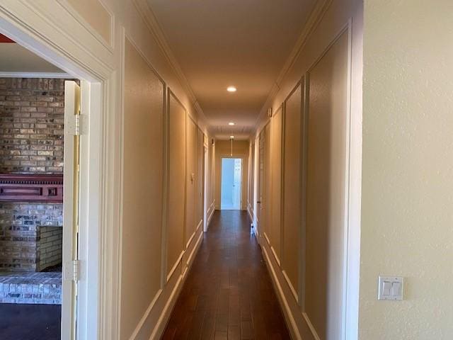 hall with recessed lighting, ornamental molding, a decorative wall, and dark wood-style floors