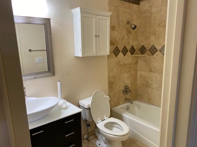 full bath with toilet, a textured wall, shower / tub combination, and vanity
