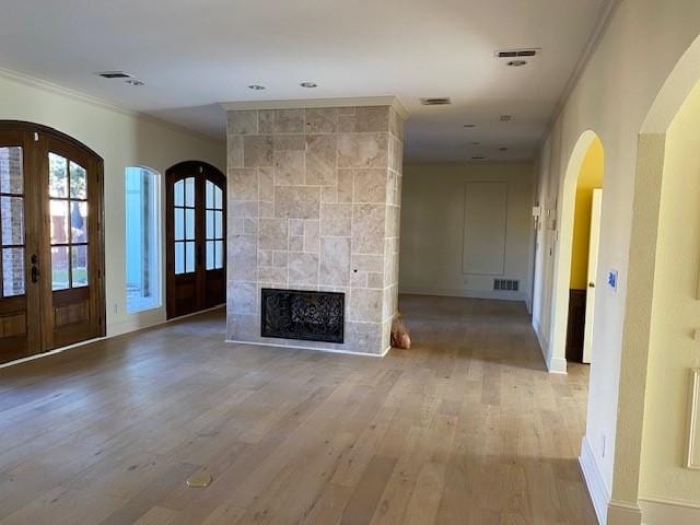 unfurnished living room featuring crown molding, visible vents, baseboards, french doors, and light wood-style flooring