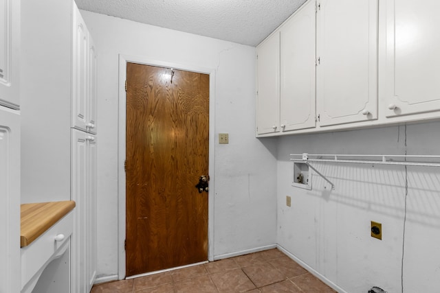 washroom featuring baseboards, a textured ceiling, cabinet space, light tile patterned floors, and hookup for an electric dryer