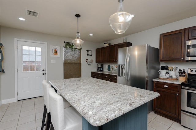kitchen featuring light tile patterned floors, stainless steel appliances, dark brown cabinets, and visible vents