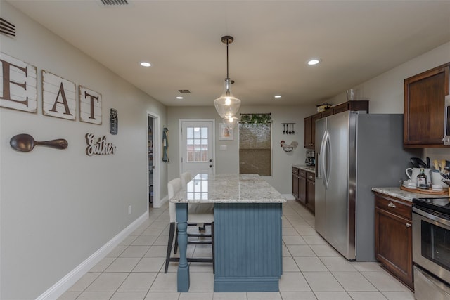 kitchen featuring pendant lighting, light tile patterned floors, a kitchen breakfast bar, a kitchen island, and appliances with stainless steel finishes