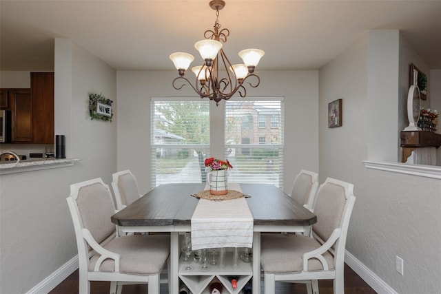 dining room with dark wood-type flooring, baseboards, and a notable chandelier