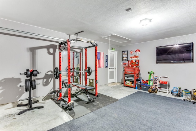 exercise area featuring attic access and a textured ceiling