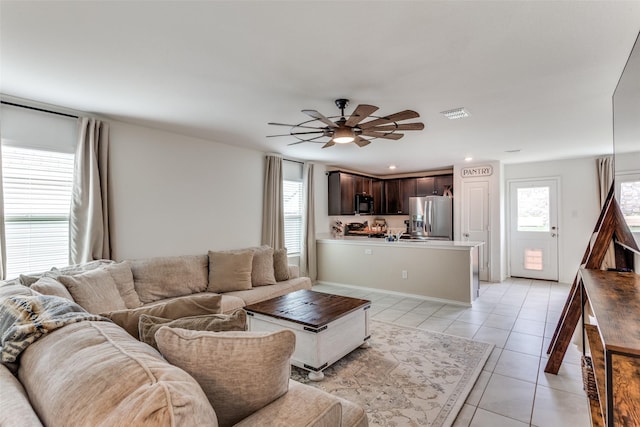 living room featuring light tile patterned floors, a ceiling fan, and visible vents