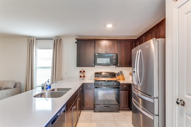kitchen featuring dark brown cabinetry, a sink, light countertops, black appliances, and light tile patterned flooring