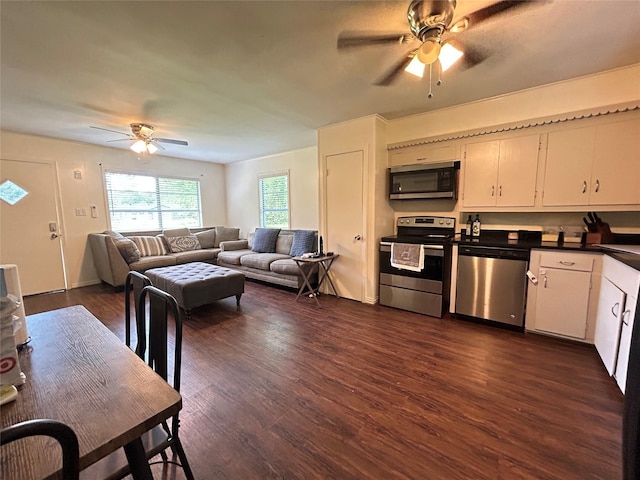kitchen with dark countertops, stainless steel appliances, a ceiling fan, white cabinetry, and dark wood-style floors