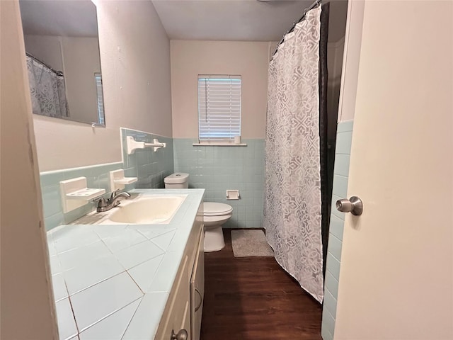 bathroom with vanity, wainscoting, wood finished floors, toilet, and tile walls