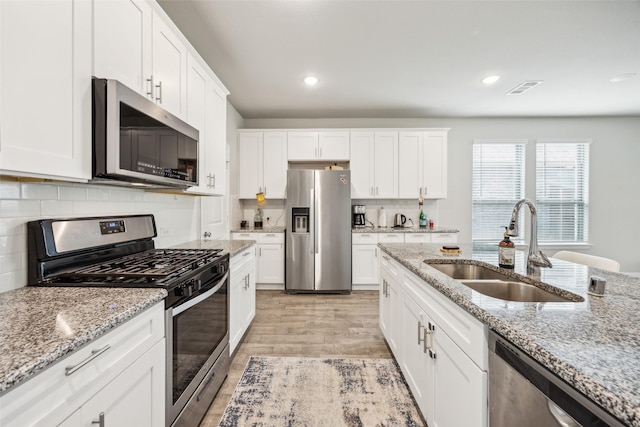 kitchen featuring a sink, light wood finished floors, appliances with stainless steel finishes, and white cabinets
