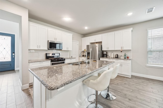kitchen with appliances with stainless steel finishes, a sink, a breakfast bar area, baseboards, and tasteful backsplash