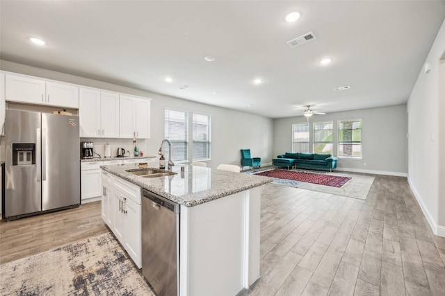 kitchen featuring visible vents, a sink, light wood-style flooring, and stainless steel appliances