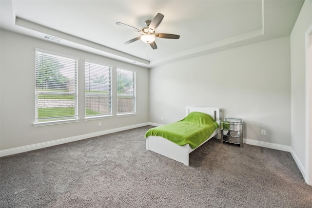 carpeted bedroom with visible vents, a ceiling fan, a raised ceiling, and baseboards