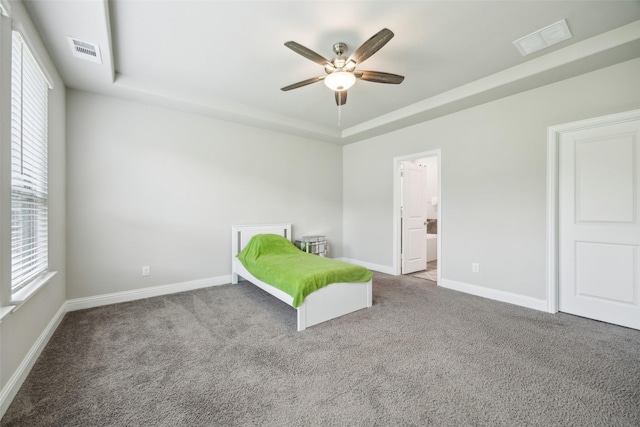 carpeted bedroom featuring visible vents, a raised ceiling, ceiling fan, and baseboards