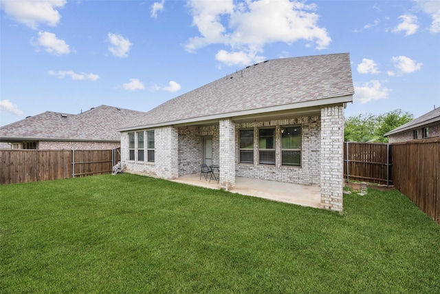 rear view of house featuring a shingled roof, brick siding, a fenced backyard, a patio area, and a lawn
