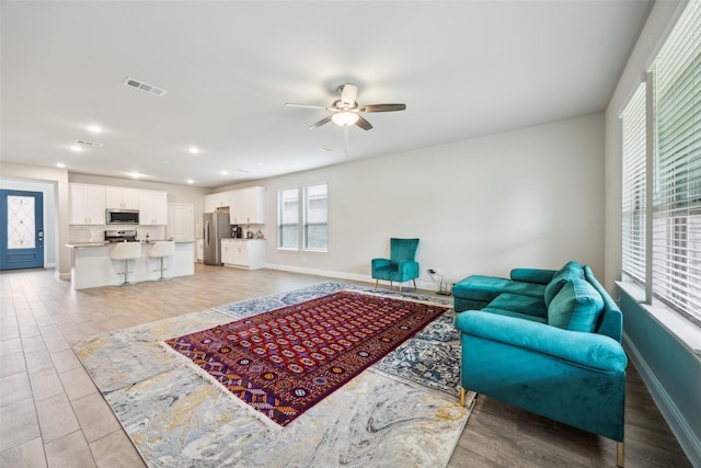 living area featuring a ceiling fan, baseboards, visible vents, and recessed lighting
