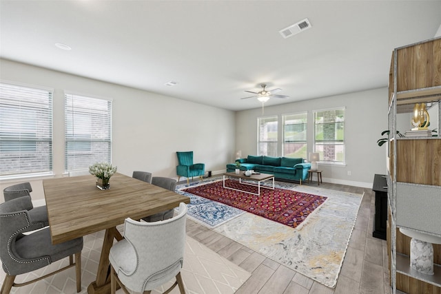 living area with visible vents, a ceiling fan, baseboards, and light wood-type flooring
