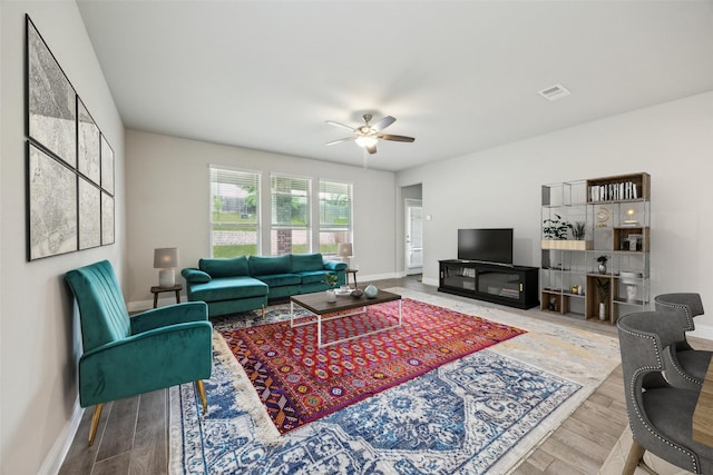living area with visible vents, a ceiling fan, baseboards, and wood finished floors