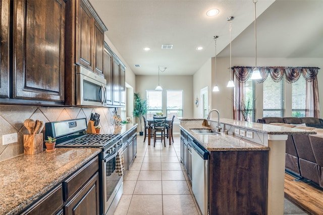 kitchen with appliances with stainless steel finishes, light stone counters, a sink, backsplash, and visible vents
