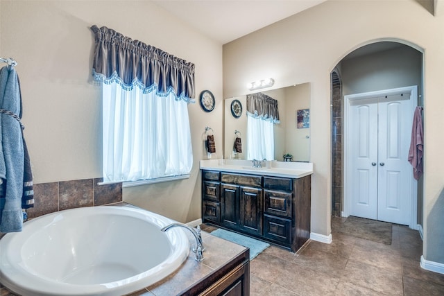 bathroom with vanity, baseboards, and a bath