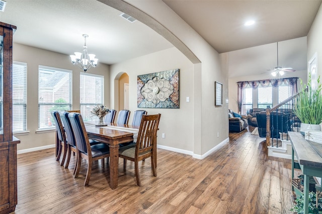 dining space with visible vents, baseboards, light wood-type flooring, arched walkways, and ceiling fan with notable chandelier