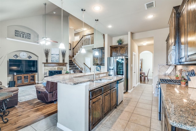 kitchen with appliances with stainless steel finishes, a sink, arched walkways, open floor plan, and visible vents