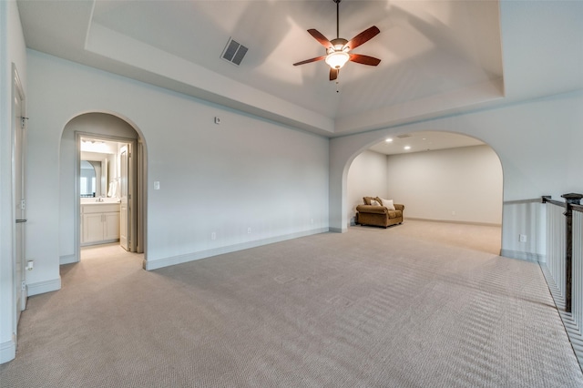 unfurnished room featuring arched walkways, a ceiling fan, and light carpet