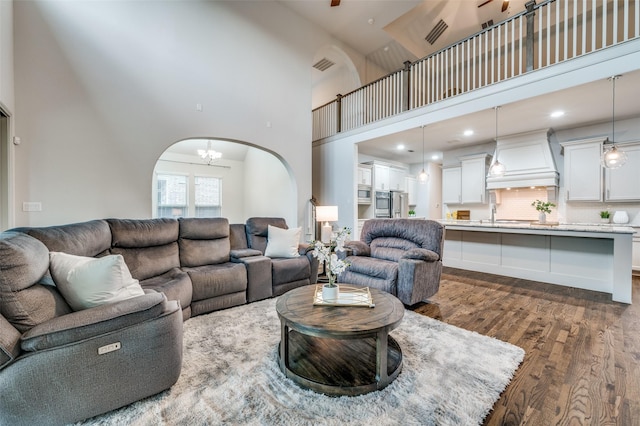 living room with visible vents, a chandelier, a high ceiling, and dark wood-style floors