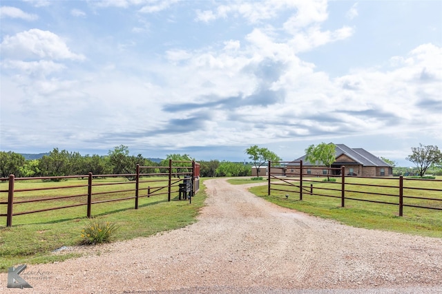 view of road with a gated entry, a rural view, and driveway