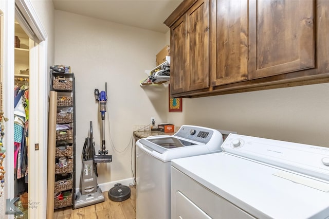 washroom featuring baseboards, cabinet space, light wood finished floors, and washing machine and dryer