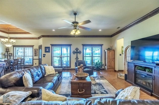 living area featuring baseboards, ornamental molding, ceiling fan with notable chandelier, and wood finished floors