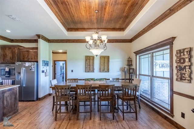 dining area featuring light wood-style floors, a tray ceiling, a chandelier, and visible vents