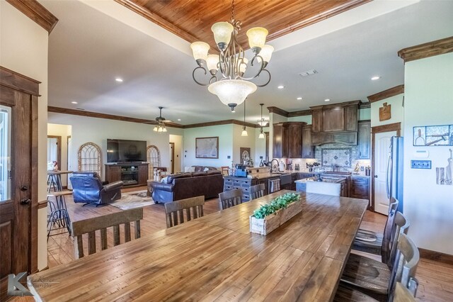 dining space with crown molding, recessed lighting, ceiling fan with notable chandelier, and wood finished floors
