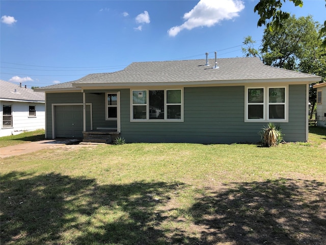 back of house with a garage, roof with shingles, a yard, and driveway